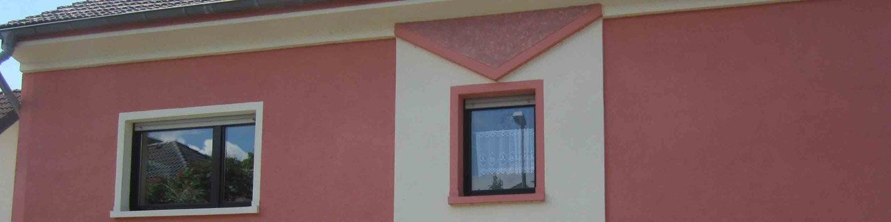 Rote Fassade mit Relief und verschiedenen Putzstrukturen um die Fenster